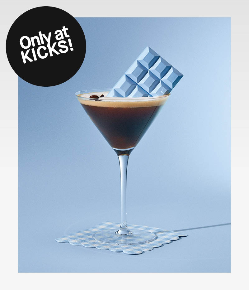 En Espresso Martini mot ljusblå bakgrund, med Sabrina Carpenters parfymflaska Me Espresso som ligger i glaset. En svart sticker med texten "Only at KICKS!"