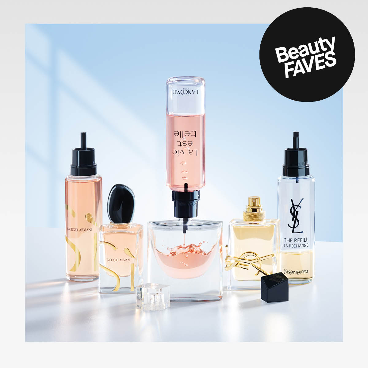 kauneustuotteita, mukaan lukien Giorgio Armani, Lancôme ja Yves Saint Laurent -tuotteet. Keskellä on Lancôme La Vie Est Belle -tuotteen pullo, joka on käännetty ylösalaisin ja täyttää lasia. Kuvan oikeassa yläkulmassa on "Beauty FAVES" -teksti.