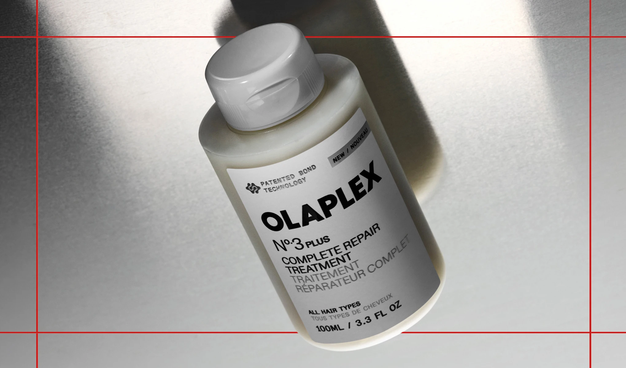 Hiustenhoitotuote OLAPLEX No.3 Plus Complete Repair Treatment valkoisessa pullossa vaaleaa taustaa vasten varjojen kanssa. Pakkauksessa näkyvät tekstit “PATENTED BOND TECHNOLOGY”, “NEW”, “OLAPLEX No.3 PLUS”, “COMPLETE REPAIR TREATMENT”, “ALL HAIR TYPES” ja “100ML / 3.3 FL OZ”.