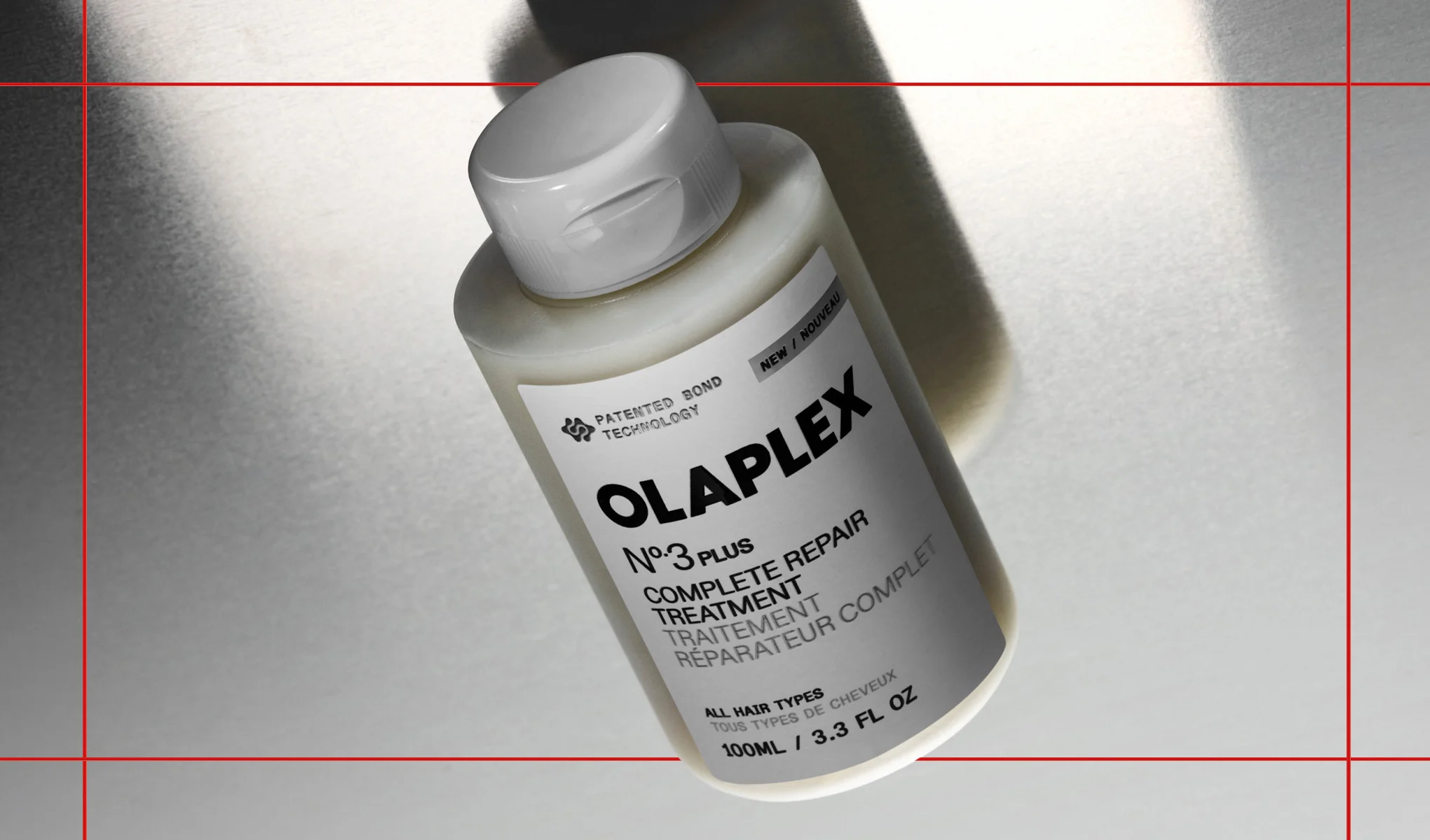 Hiustenhoitotuote OLAPLEX No.3 Plus Complete Repair Treatment valkoisessa pullossa vaaleaa taustaa vasten varjojen kanssa. Pakkauksessa näkyvät tekstit “PATENTED BOND TECHNOLOGY”, “NEW”, “OLAPLEX No.3 PLUS”, “COMPLETE REPAIR TREATMENT”, “ALL HAIR TYPES” ja “100ML / 3.3 FL OZ”.