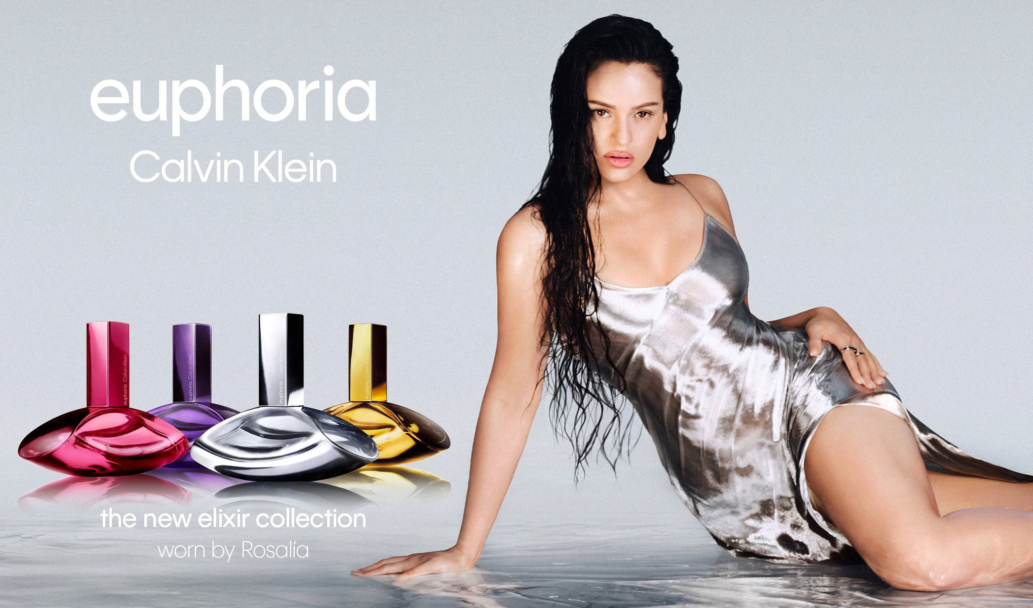 Kvinna i silverfärgad klänning och fyra Calvin Klein Euphoria-parfymflaskor. Text: ”Euphoria Calvin Klein. The new elixir collection. Worn by Rosalía.”