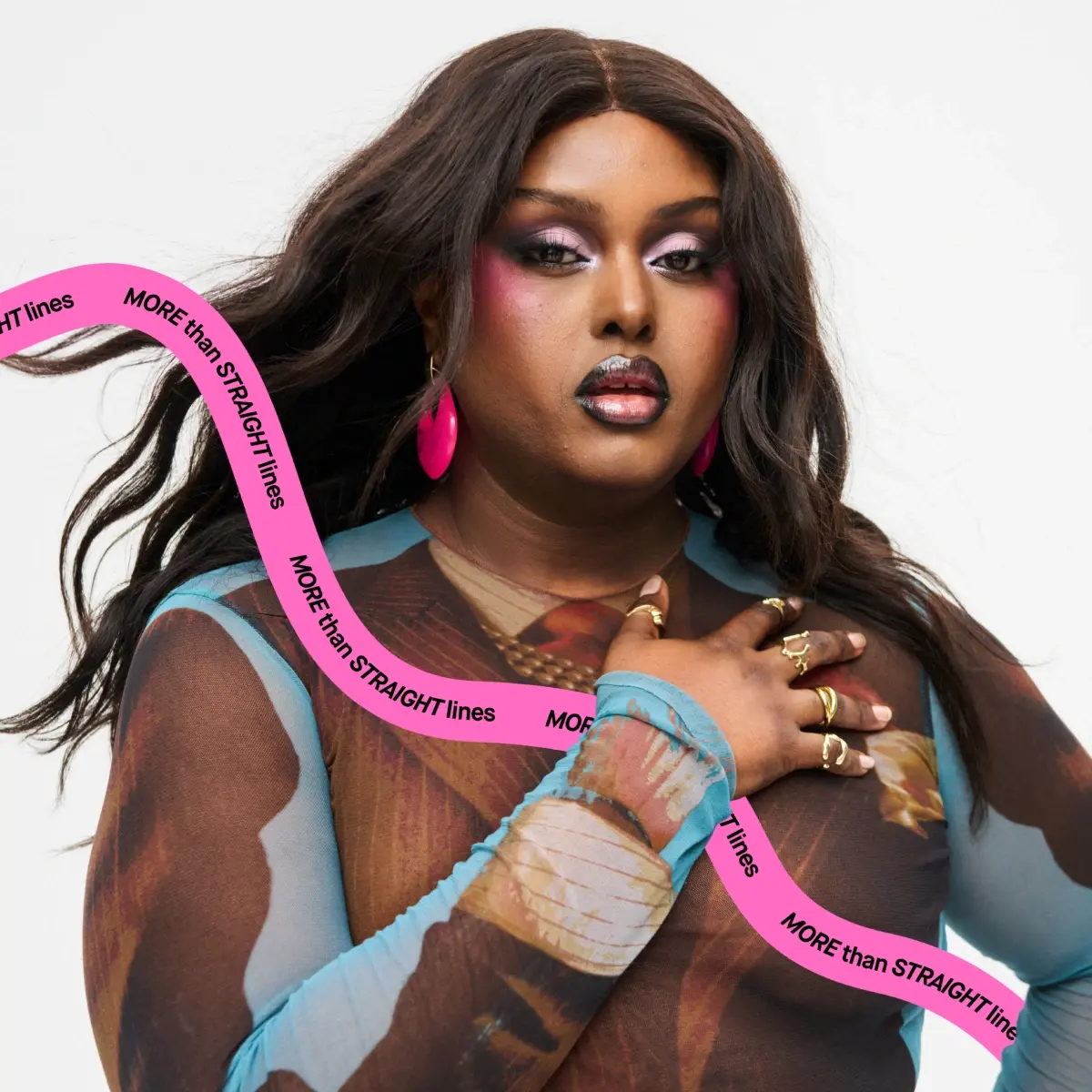 Närbild på person med långt mörkt hår, rosa makeup och rosa örhängen som håller handen mot bröstet och bär transparent mönstrad meshtopp. Rosa grafisk linje med texten “MORE than STRAIGHT lines” mot ljusgrå bakgrund.