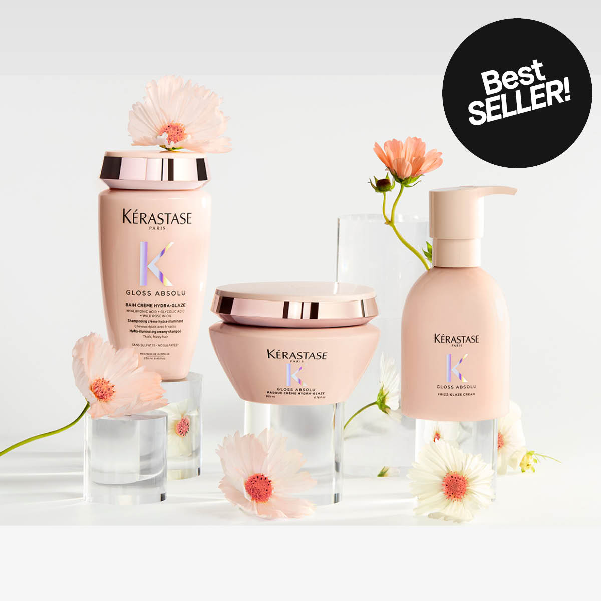 Kérastase Gloss Absolu hårprodukter mot ljus bakgrund: schampo, hårmask och vårdande kräm omgivna av blommor, med ”Best seller!”-märkning.