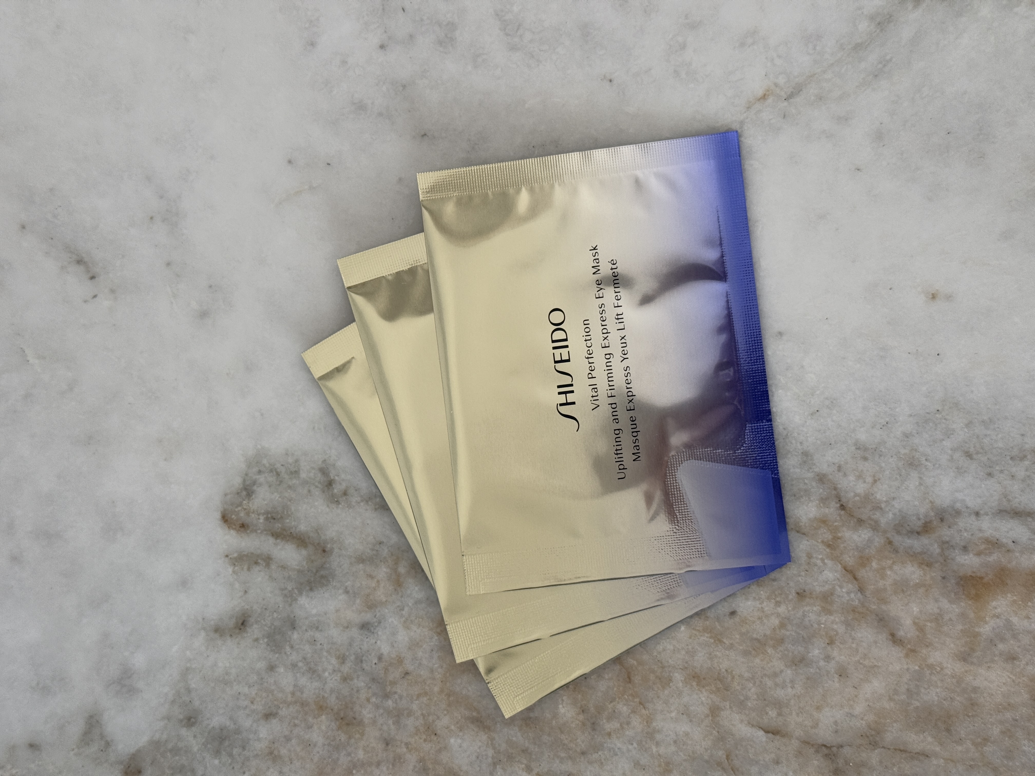 Tre pakker med Shiseido Uplifting and Firming Express Eye Mask, plassert på en marmoroverflate.