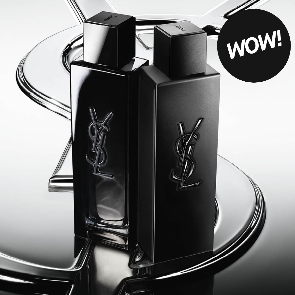 Produktbilde med teksten “WOW!” og to svarte Yves Saint Laurent parfymeflasker med YSL-logo mot metallisk sølvbakgrunn.