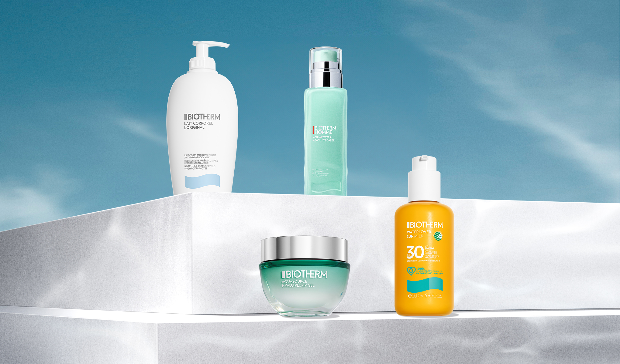 Fyra Biotherm-produkter placerade på vita plattformar mot en blå himmel.