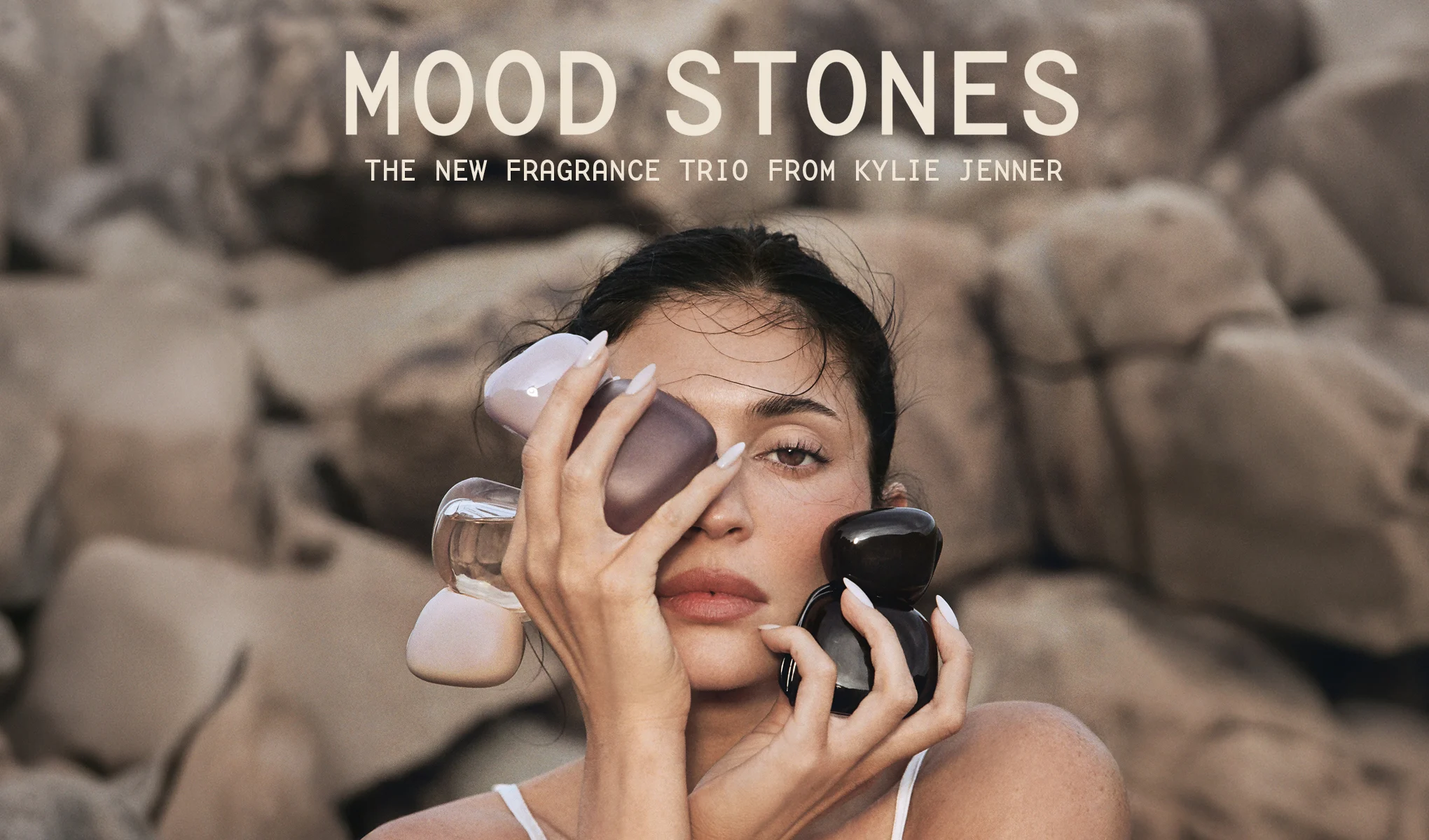 Kvinna håller tre Mood Stones-parfymflaskor framför ansiktet.