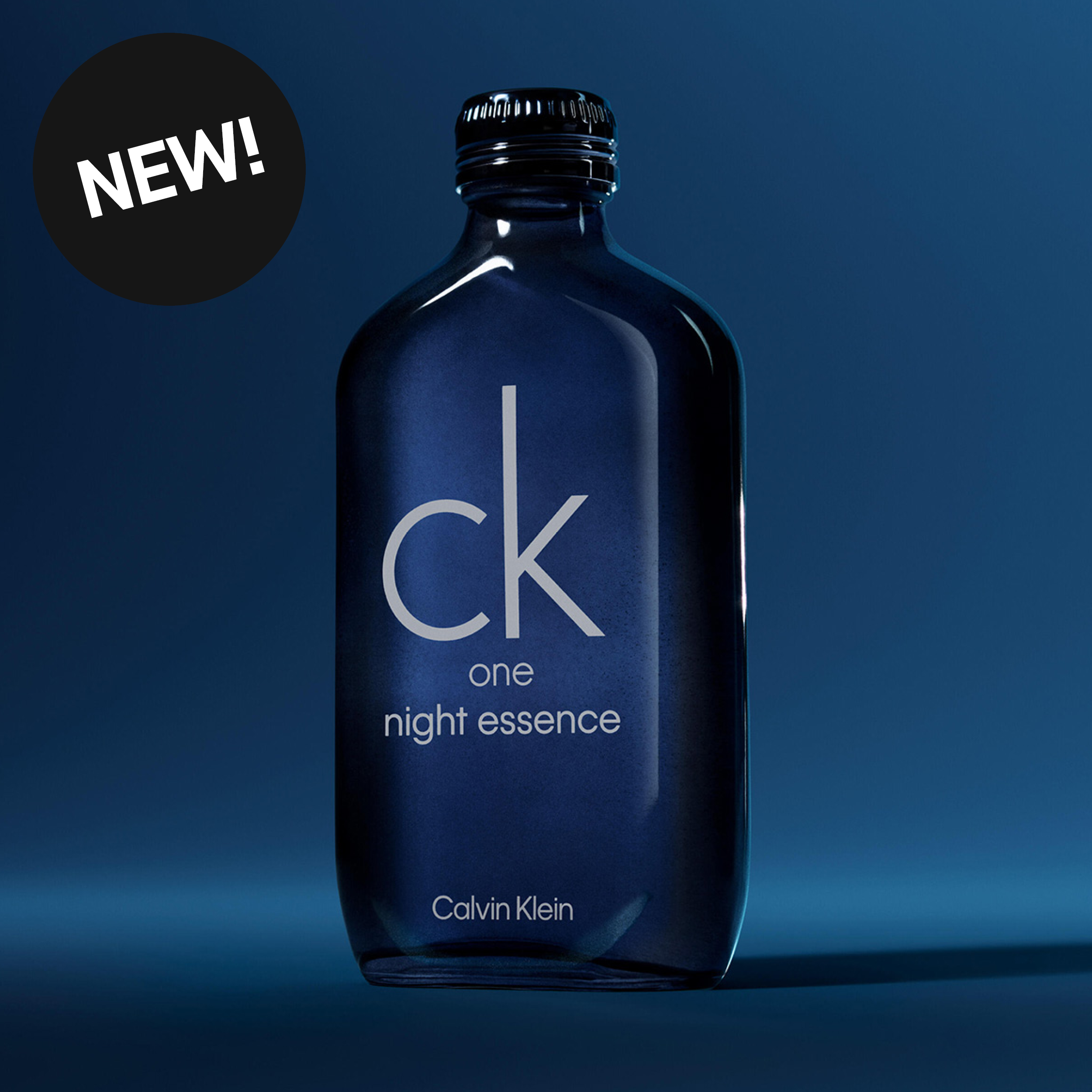 Calvin Klein CK One Night Essence -hajuvesi tummansinisessä pullossa, jossa teksti “ck one night essence Calvin Klein” sekä musta ympyrä tekstillä “WOW!”.
