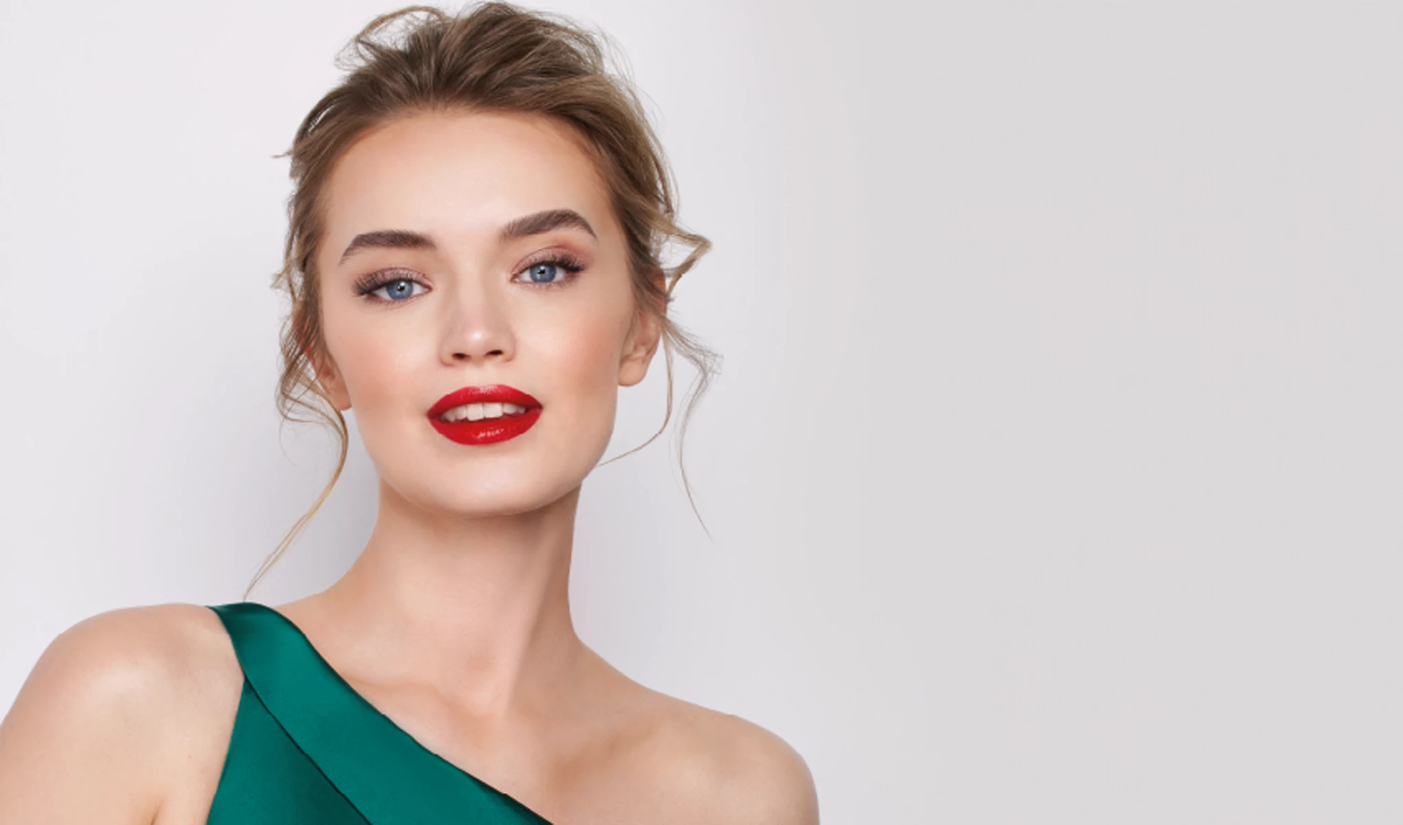 Artdeco modell med uppsatt hår som bär en grön klänning med one shoulder. Bakgrunden är ljus och enkel.