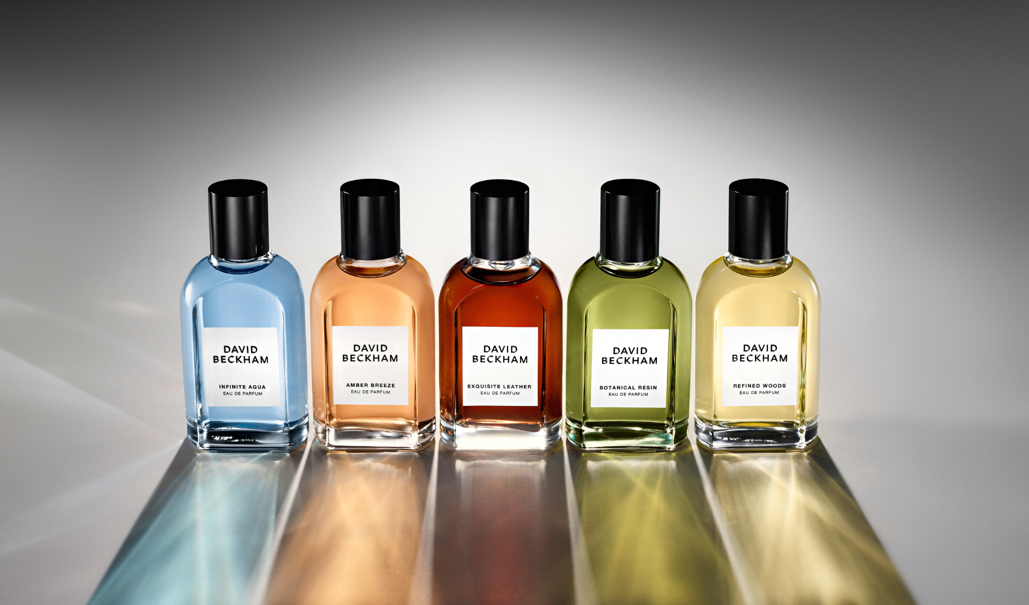 En mann sitter på en mosegrodd trestamme i skogen og ser rett mot kameraet.