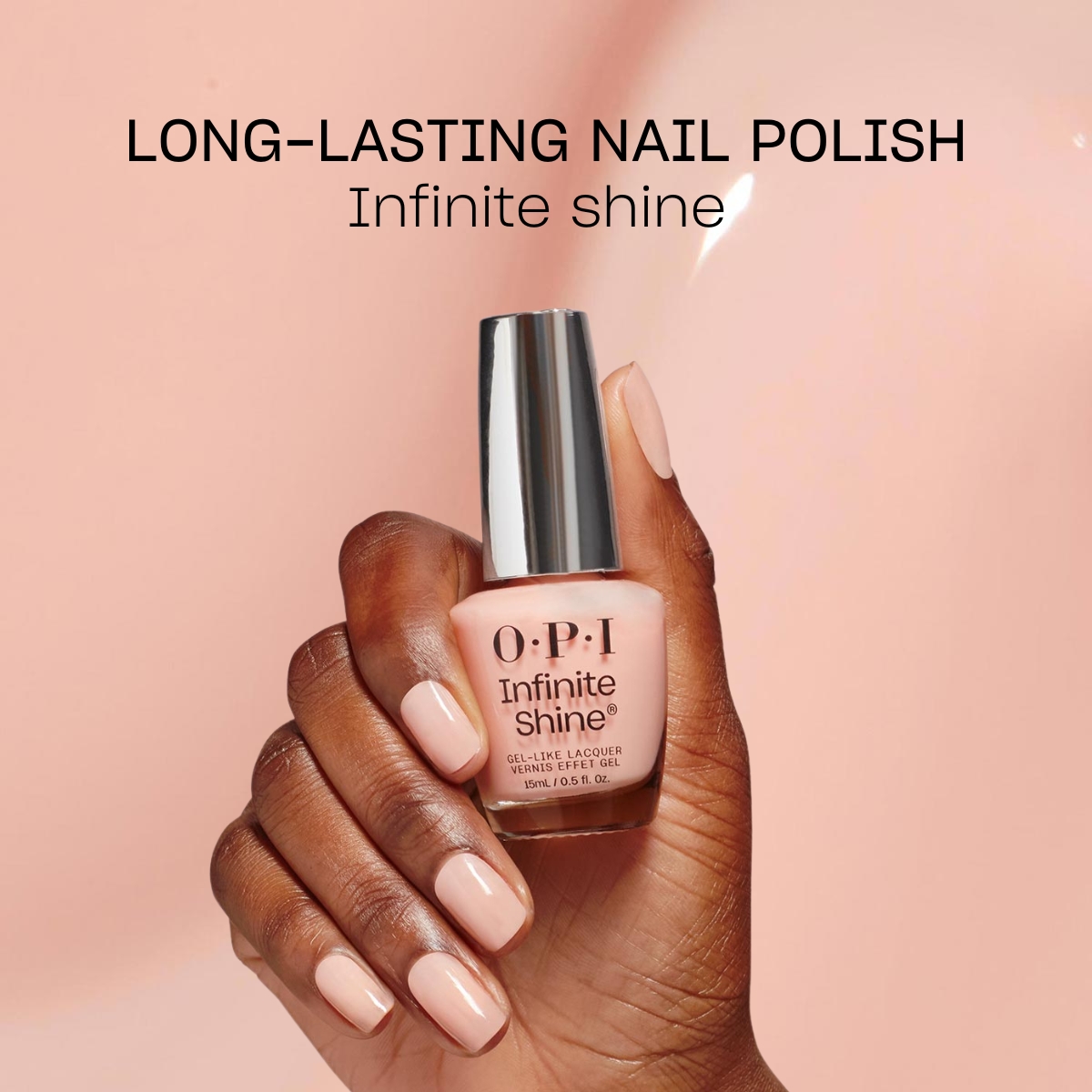 Käsi, jossa on vaaleanpunainen kynsilakka merkiltä OPI. Kädessä on kynsilakkapullo nimeltä ”Infinite Shine”. Tausta on vaaleanpunainen ja kynsilakkapullon yläpuolella on teksti ”Long-Lasting Nail Polish Infinite shine”.