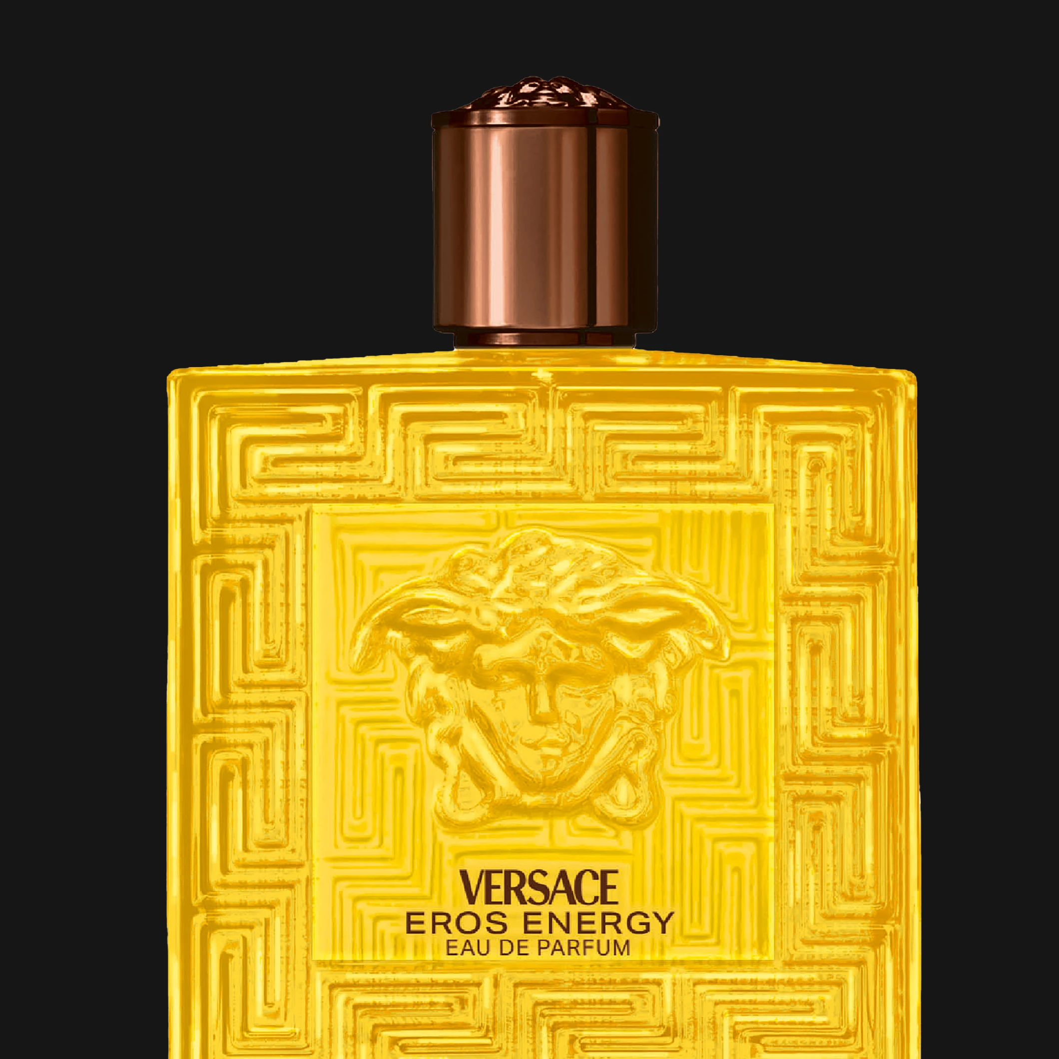 Versace Eros Energy Eau de Parfum i gul glasflaska med Medusa-motiv och dekorativt mönster mot svart bakgrund. Synlig text inkluderar “VERSACE”, “EROS ENERGY” och “EAU DE PARFUM”.