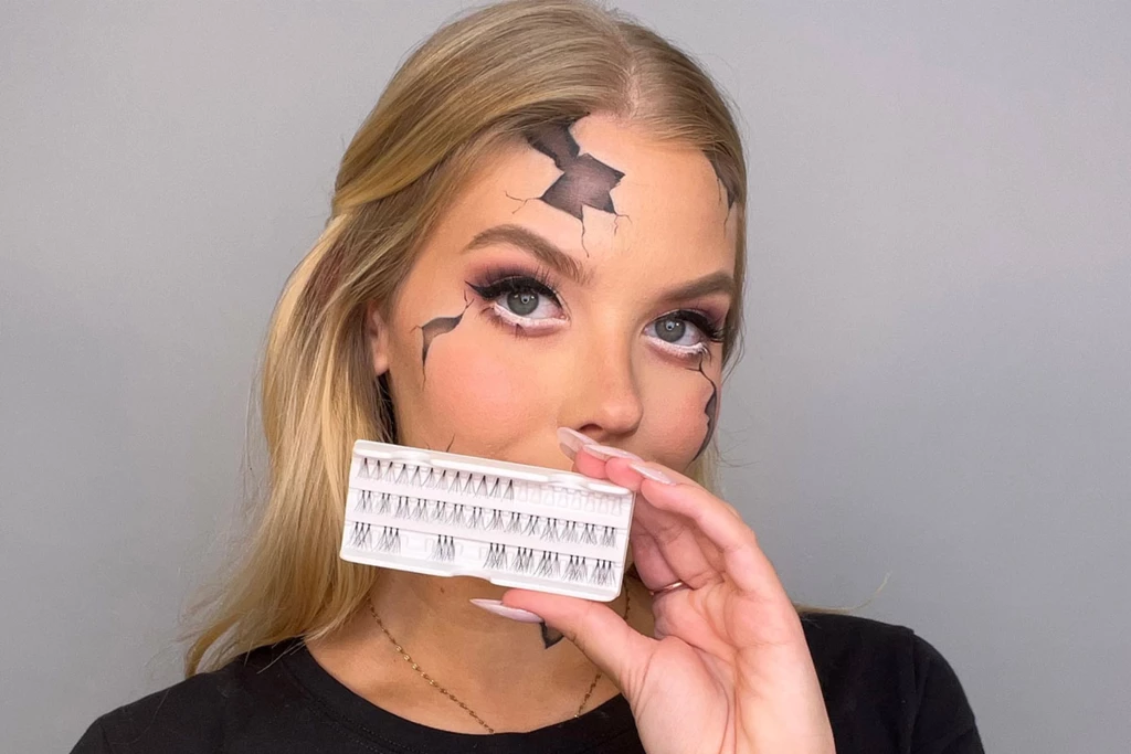 En kvinna med sprucken hud och specialeffektsmakeup håller i en bricka med enskilda lösögonfransar.