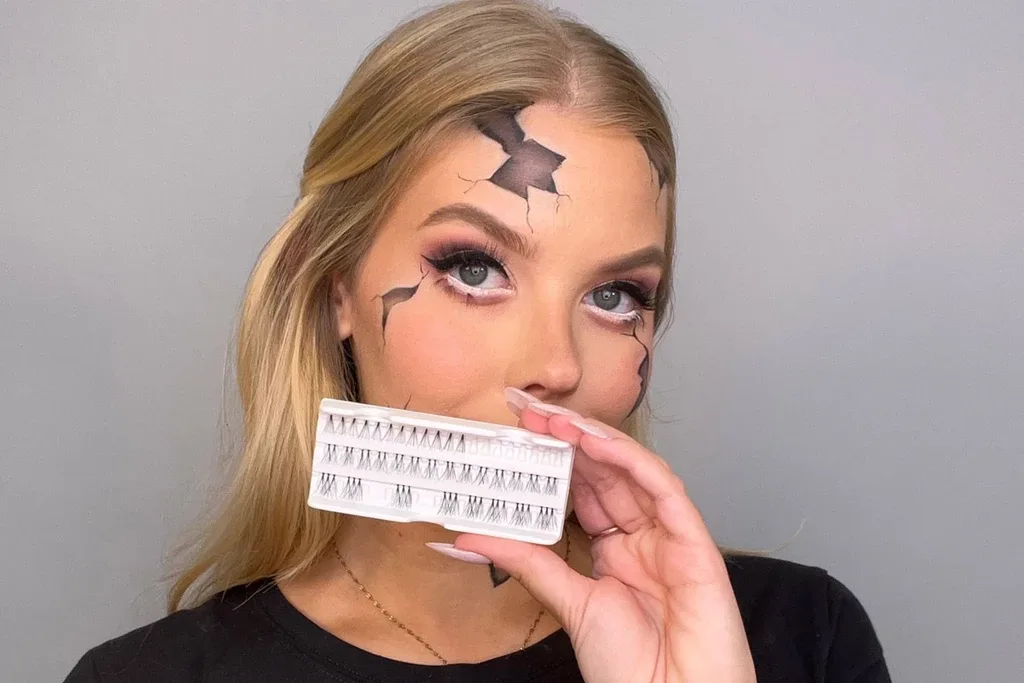 En kvinna med sprucken hud och specialeffektsmakeup håller i en bricka med enskilda lösögonfransar.