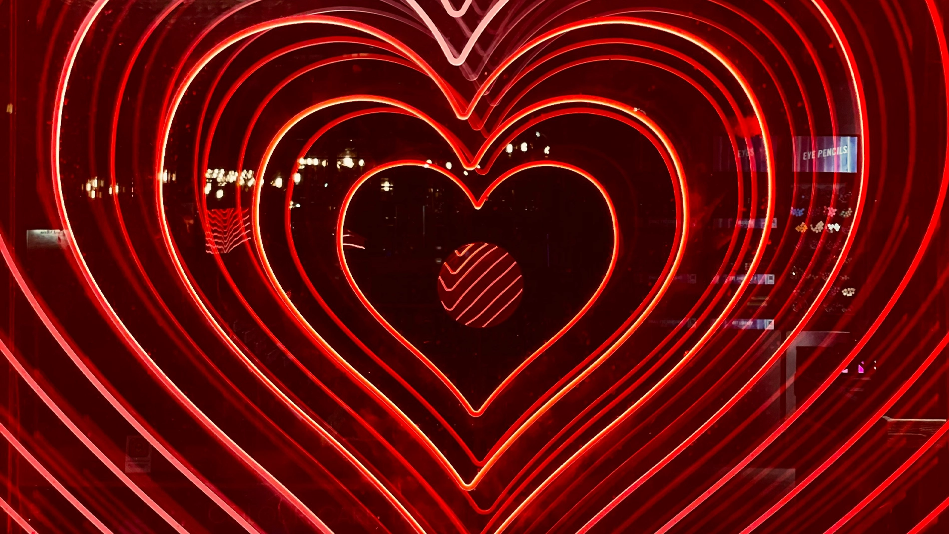 Neonlys i mørket, formet som hjerter i avtagende størrelse, med uklare bylys i bakgrunnen.