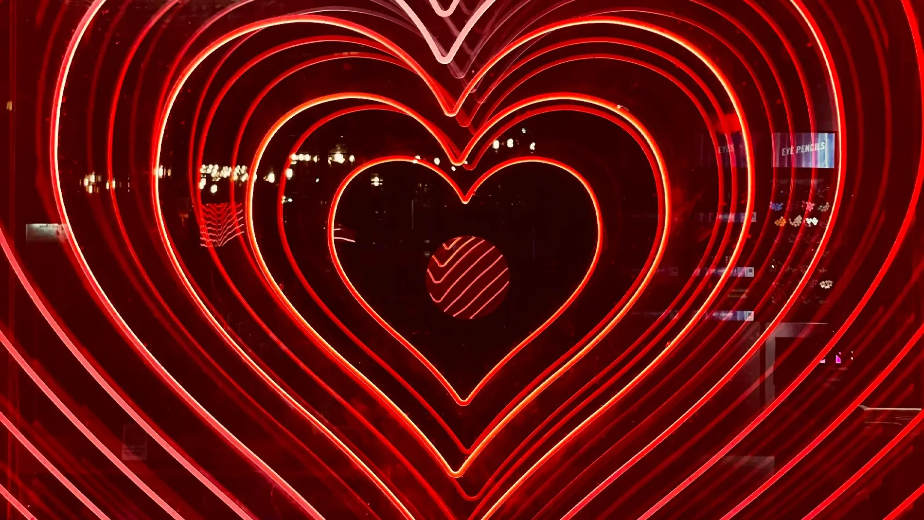 Neonlys i mørket, formet som hjerter i avtagende størrelse, med uklare bylys i bakgrunnen.