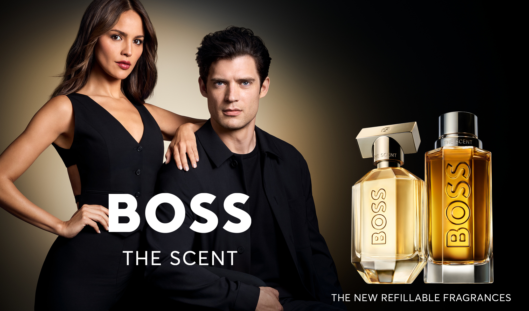 Kaksi ihmistä, nainen ja mies, pukeutuneina mustiin vaatteisiin, joiden kasvot olivat sumeat. Heidän vieressään on kaksi BOSSin hajuvesipulloa, joissa lukee ”Boss The Scent” ja ”The New Refillable Fragrances”. Tausta on tumma ja siinä on vaalea kaltevuus.