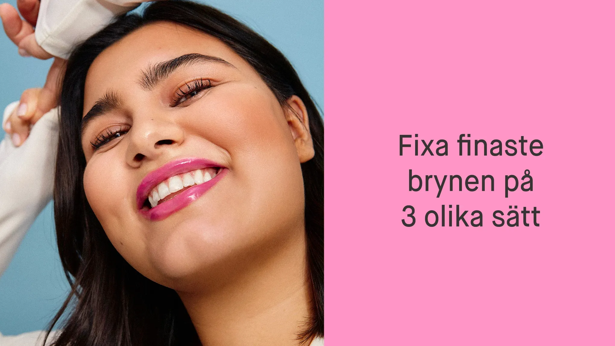 Kvinna med händerna på huvudet som ler mot kameran och bär smink med rosa läppstift, mot en blå bakgrund