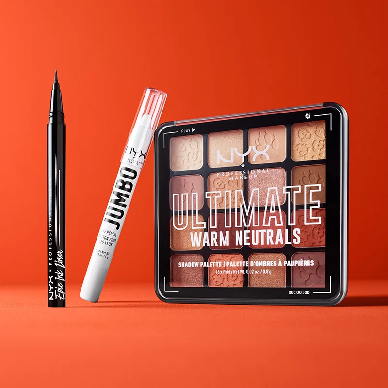 Tre NYX Professional-Makeup produkter mot en röd bakgrund. Produkterna inkluderar en svart eyelinerpenna, en vit ögonpenna och en ögonskuggspalett.