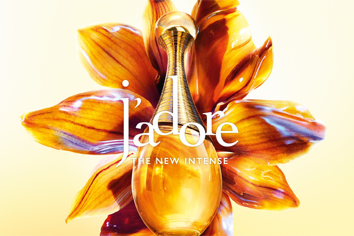 Dior J’adore parfymeflaske foran en stor gyllen blomst med teksten “j’adore” og “THE NEW INTENSE” over bildet.