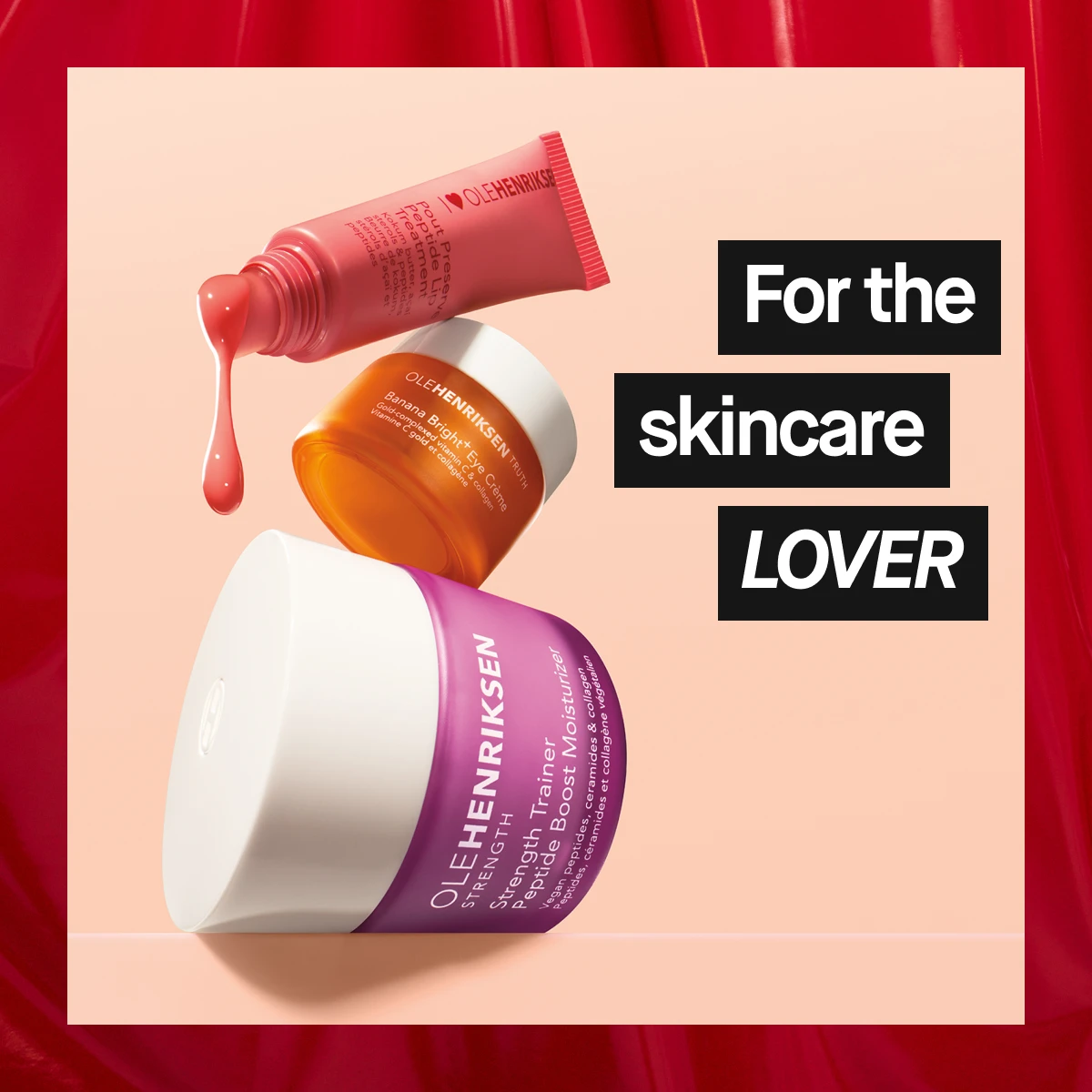 Ole Henriksen hudpleieprodukter i fargerike beholdere, inkludert en oransje krukke, en rosa tube og en lilla kremboks, mot lys bakgrunn med røde gardiner – frisk og livlig kampanjebilde for hudpleieelskere.