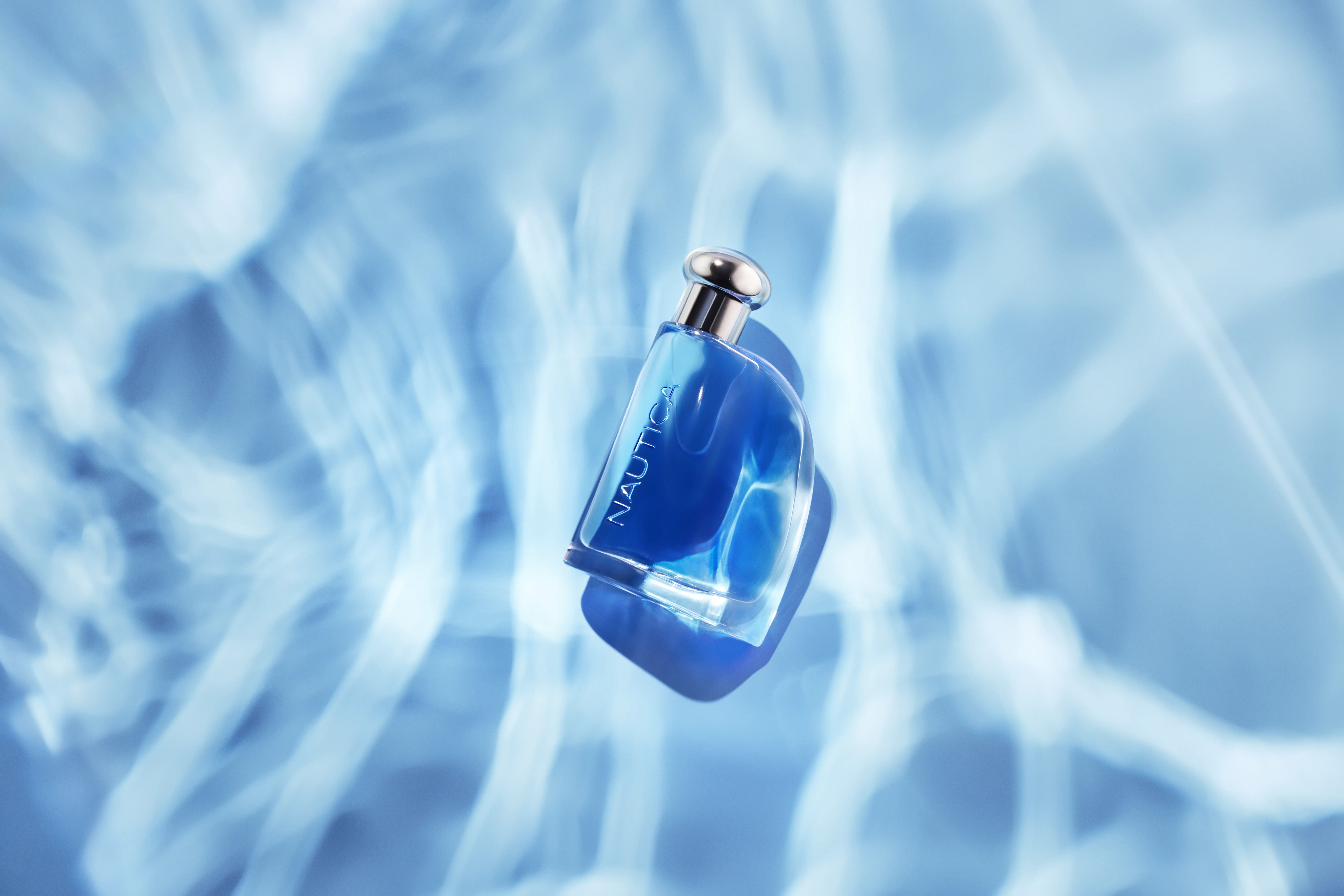 Blå Nautica-parfymflaska som verkar flyta på vattenytan.