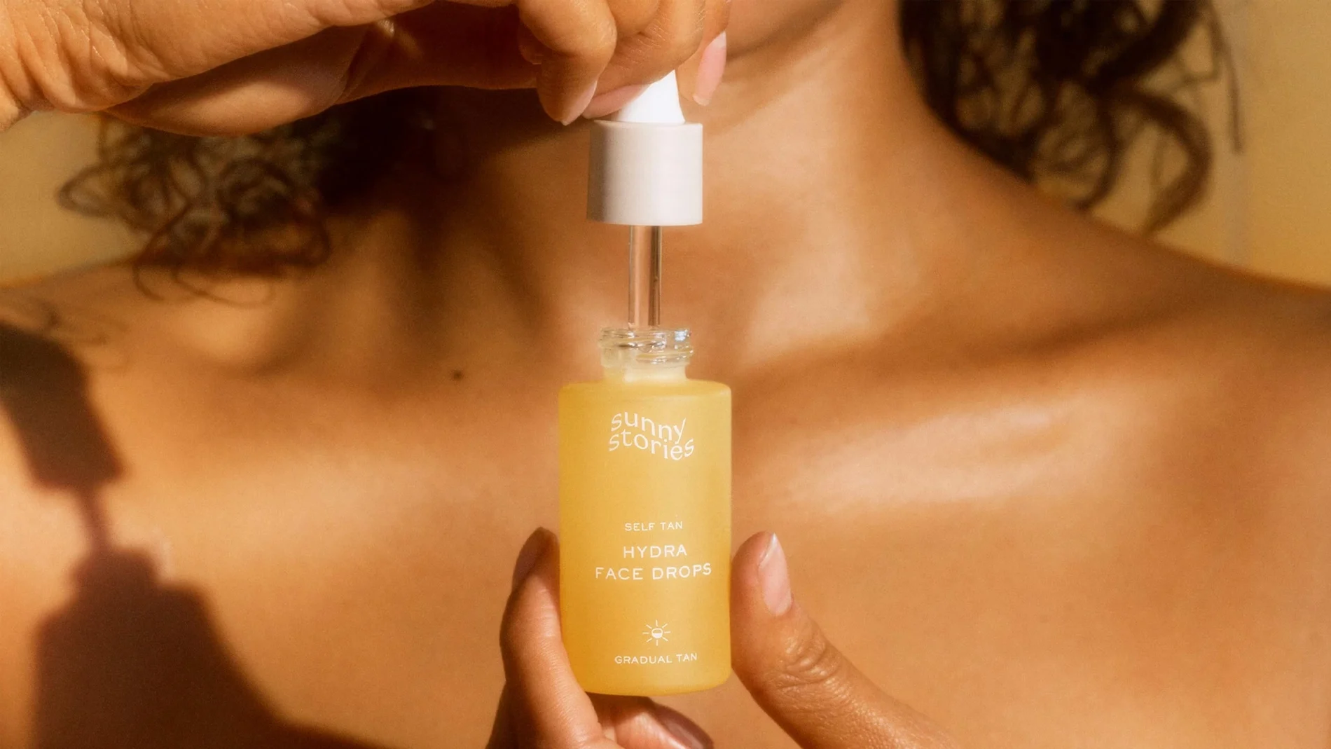 En person håller en flaska med Sunny Stories Hydra Face Drops.