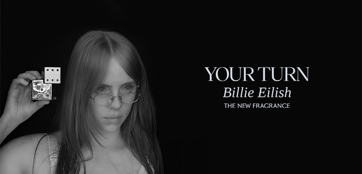 Billie Eilish pitää uutta "Your Turn" -hajuvettään kädessään. Se on muotoiltu kahdeksi päällekkäin asetetuksi nopaksi.