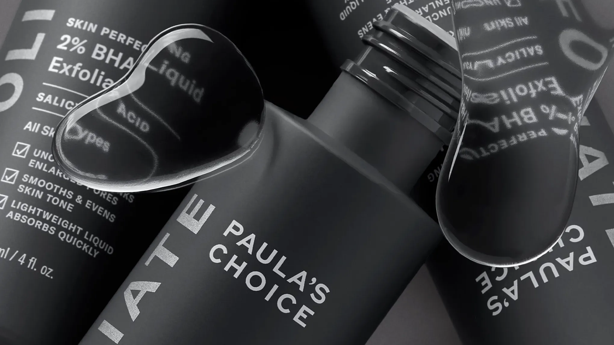 Kolme Paula's Choice -tuotetta lähikuvassa harmaalla taustalla ja vesipisaroita etualalla.