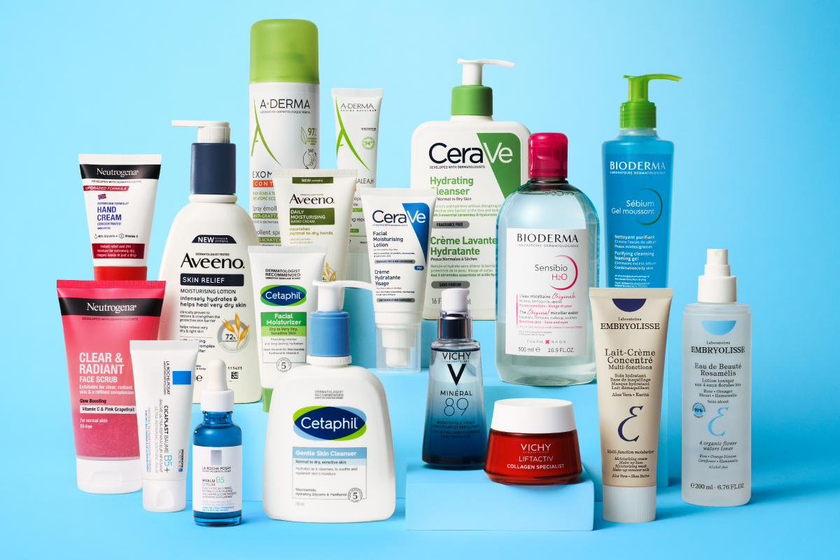 En samling hudvårdsprodukter från olika märken, inklusive Neutrogena, Aveeno, CeraVe, Bioderma, Cetaphil, Vichy och Embryolisse, mot en blå bakgrund.