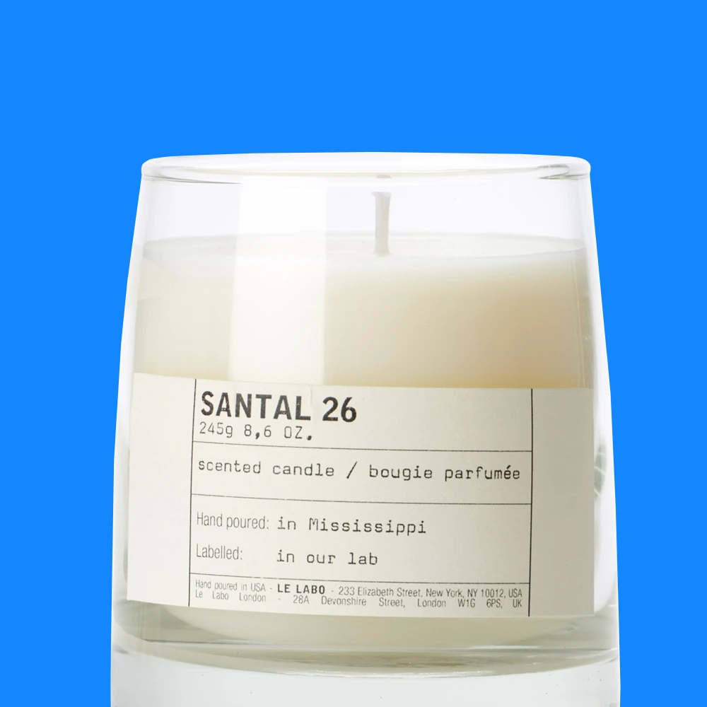Santal 26 doftljus i glasbehållare mot en blå bakgrund.