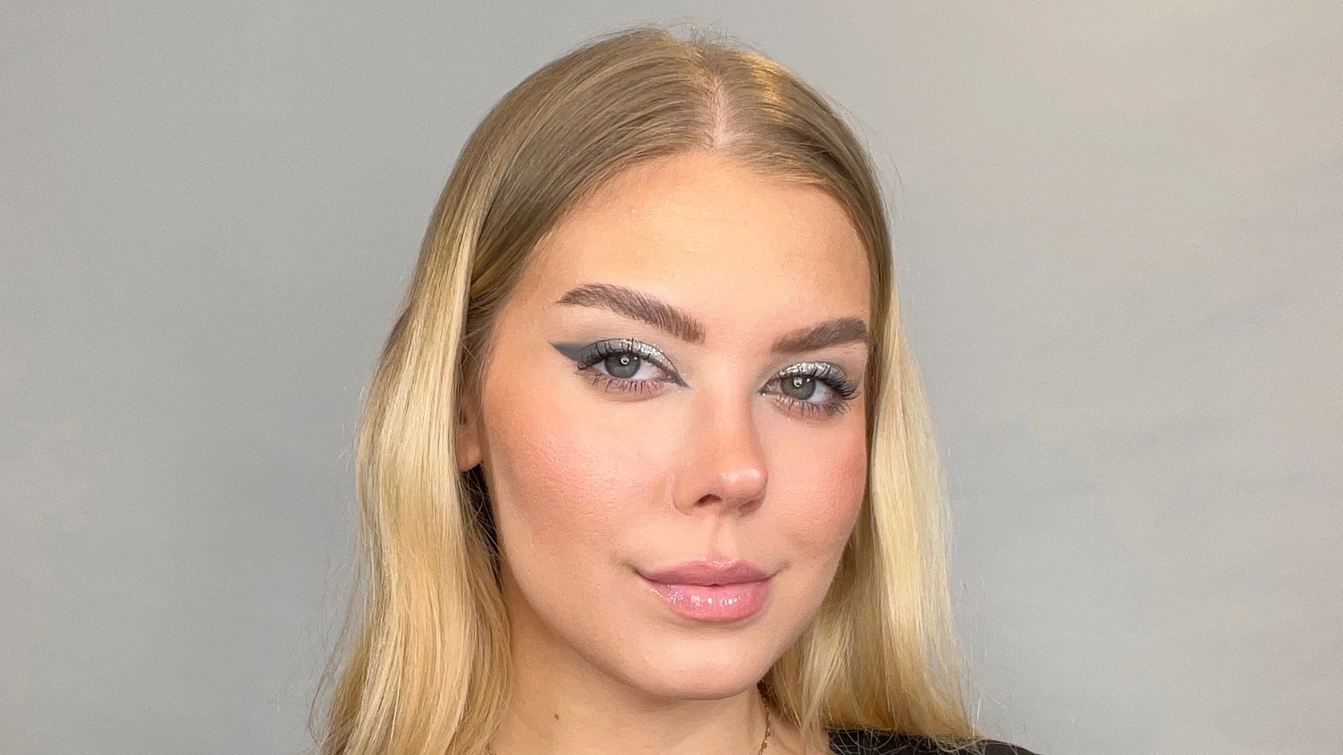 Nainen kimaltelevassa hopeameikissä ja eyelinerissa.