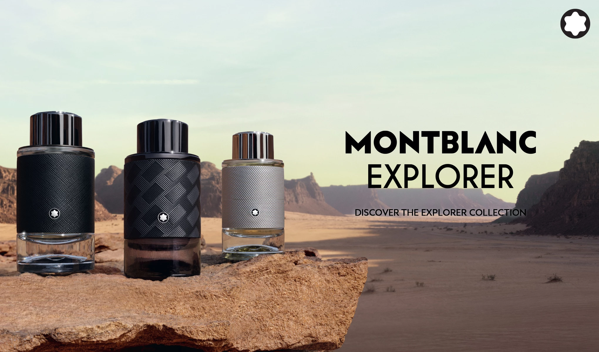 Tre Montblanc Explorer-parfymeflasker står på en stein med ørkenlandskap i bakgrunnen. Teksten "Montblanc Explorer - Discover the Explorer Collection" vises til høyre.