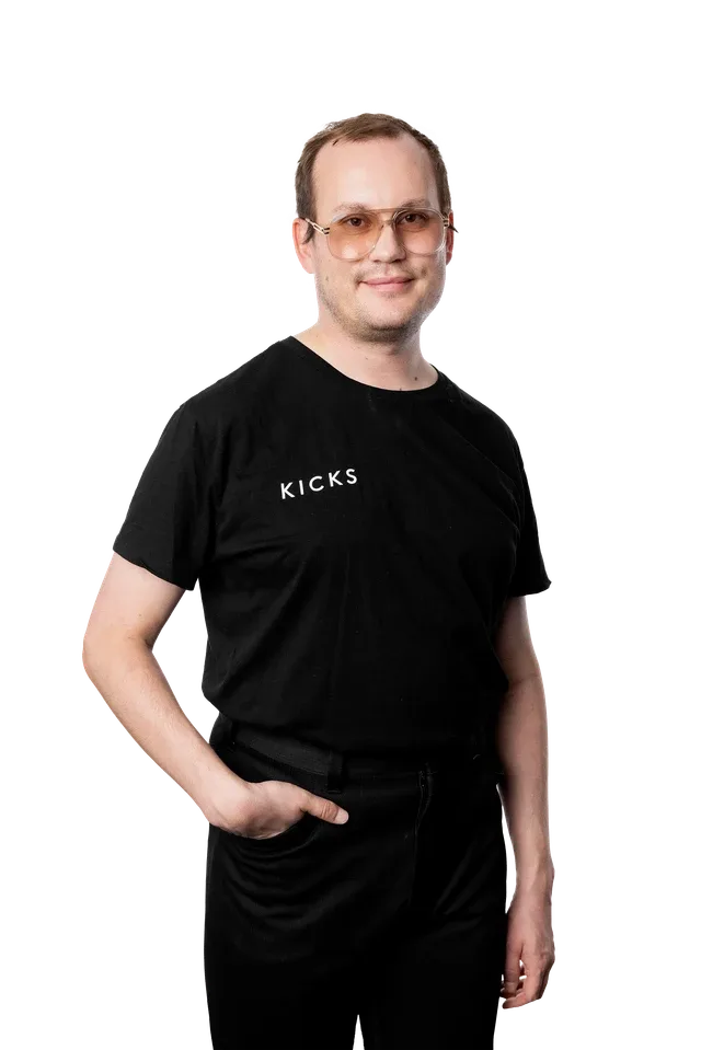 Hymyilevä KICKSin kauneusasiantuntija mustassa logopaidassa mustaa taustaa vasten