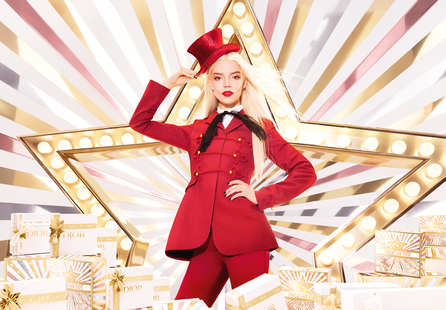 Dior joulukampanja, nainen punaisessa puvussa kirkkaiden valojen ja tähtitaustan edessä.