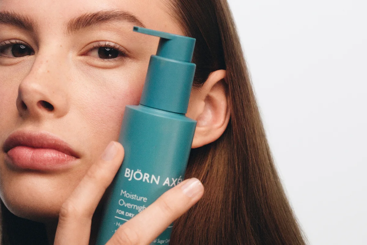 Kvinna håller Björn Axén Moisture Overnight Miracle Treatment intill ansiktet.