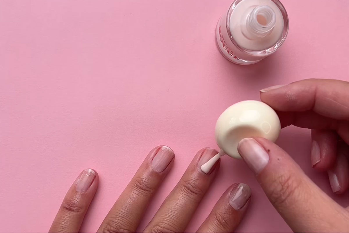 Hand och nagellack mot en rosa bakgrund 