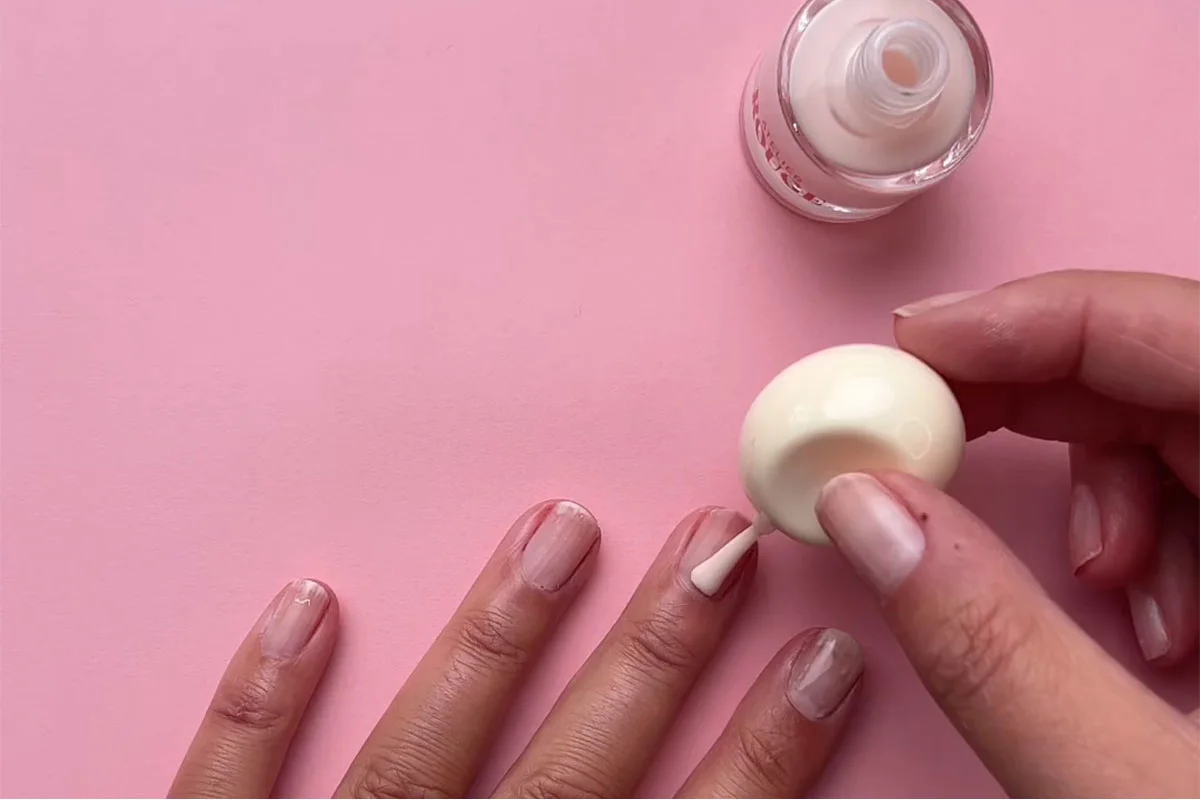Hand och nagellack mot en rosa bakgrund 