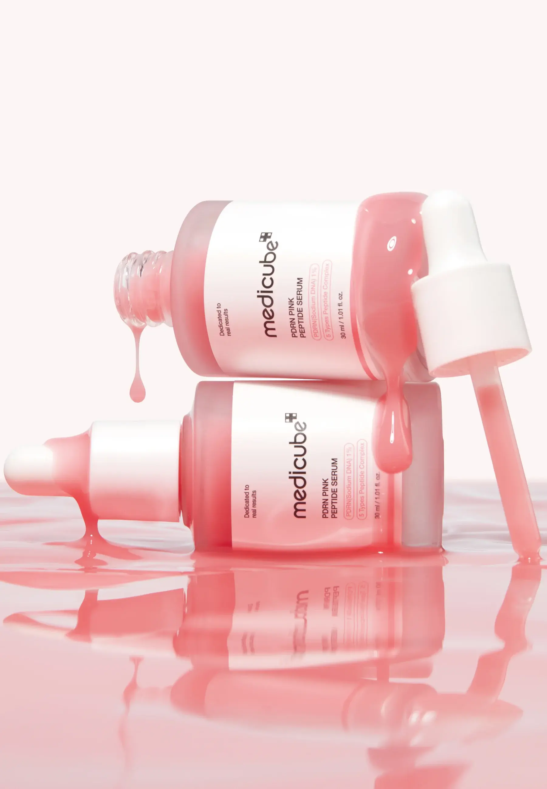 To flasker Medicube PDRN Pink Peptide Serum, med rosa serum som renner over og drypper.