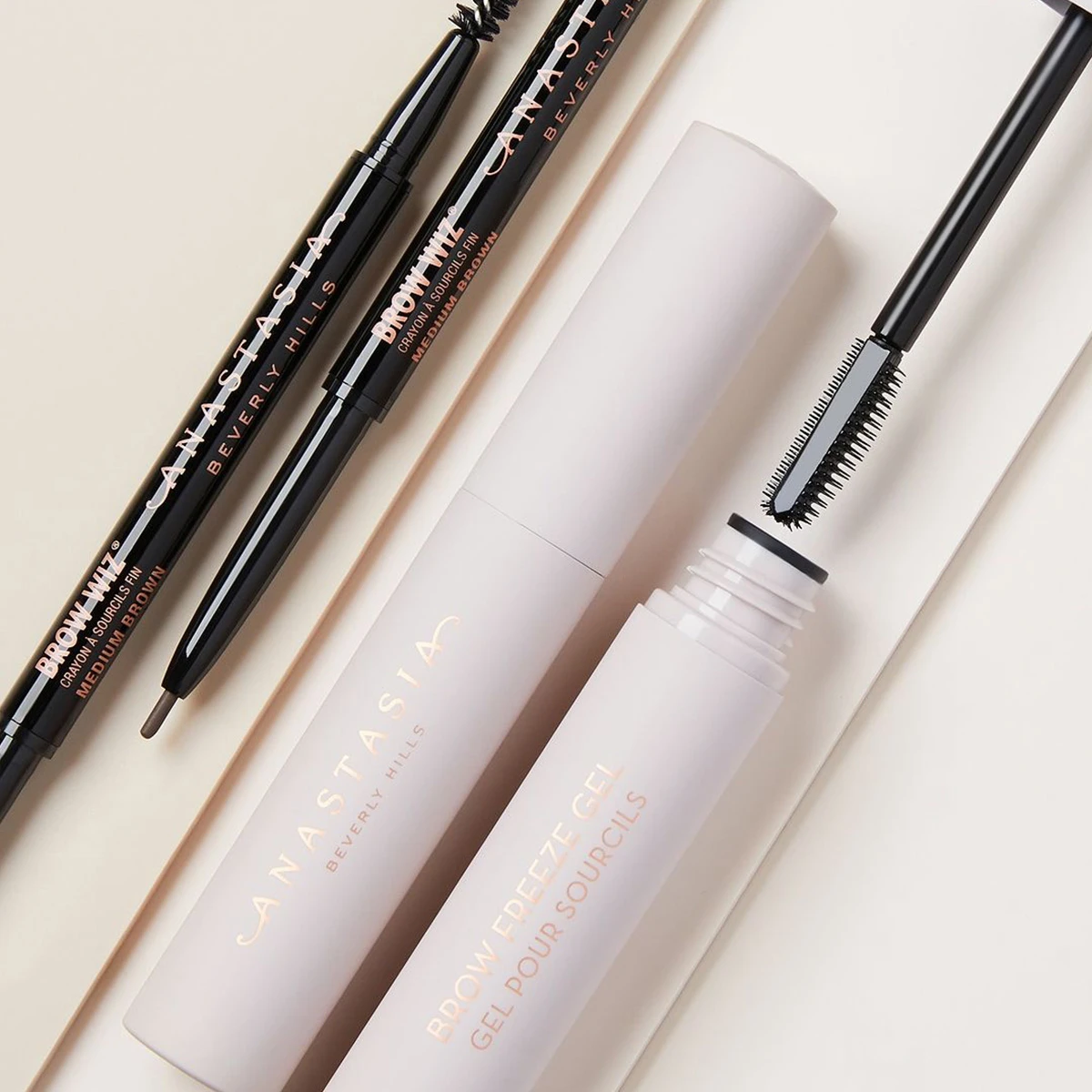 Bilde av tre skjønnhetsprodukter fra Anastasia Beverly Hills: to øyenbrynsblyanter i fargen Medium Brown og en øyenbrynsgel med børste.