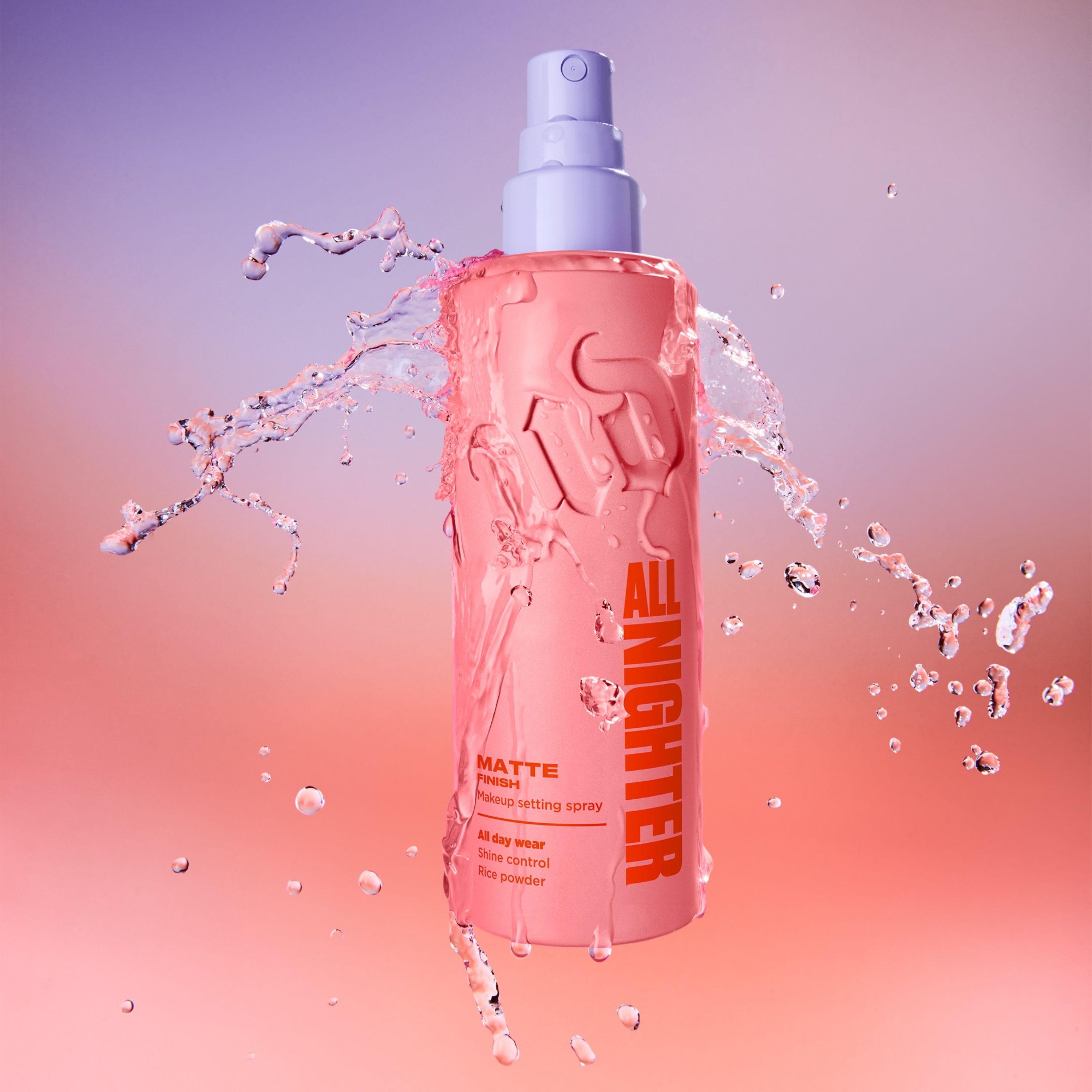 Person holder Urban Decay All Nighter Matte setting spray i rosa flaske med lilla spraypumpe. På flasken vises teksten “ALL NIGHTER” og “MATTE”.