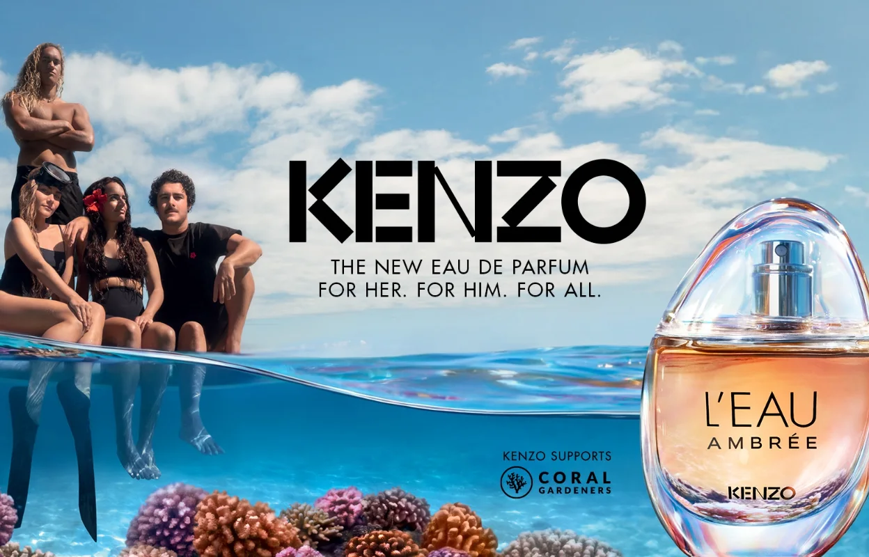 Tre personer sitter vid havsytan ovanför ett korallrev medan Kenzo-parfymen L’EAU AMBRÉE visas till höger i bilden. Texten ”KENZO”, ”THE NEW EAU DE PARFUM FOR HER. FOR HIM. FOR ALL.” samt ”KENZO SUPPORTS CORAL GARDENERS” syns tillsammans med produktnamnet på parfymflaskan.