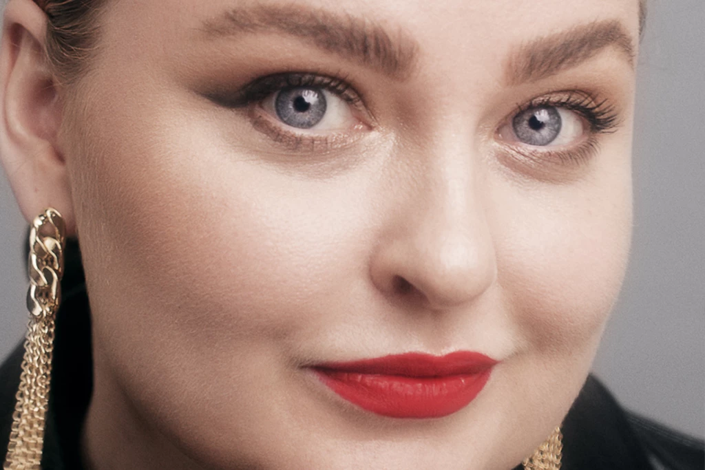 Kvinna med guldörhängen, cat eye-makeup och rött läppstift.