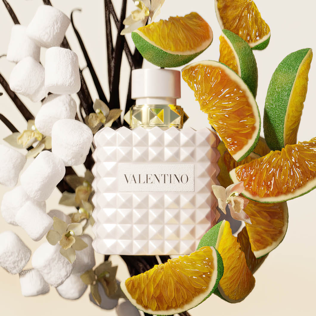 Vit Valentino parfymflaska omgiven av mashmallows, vaniljstänger, blommor och apelsinskivor.