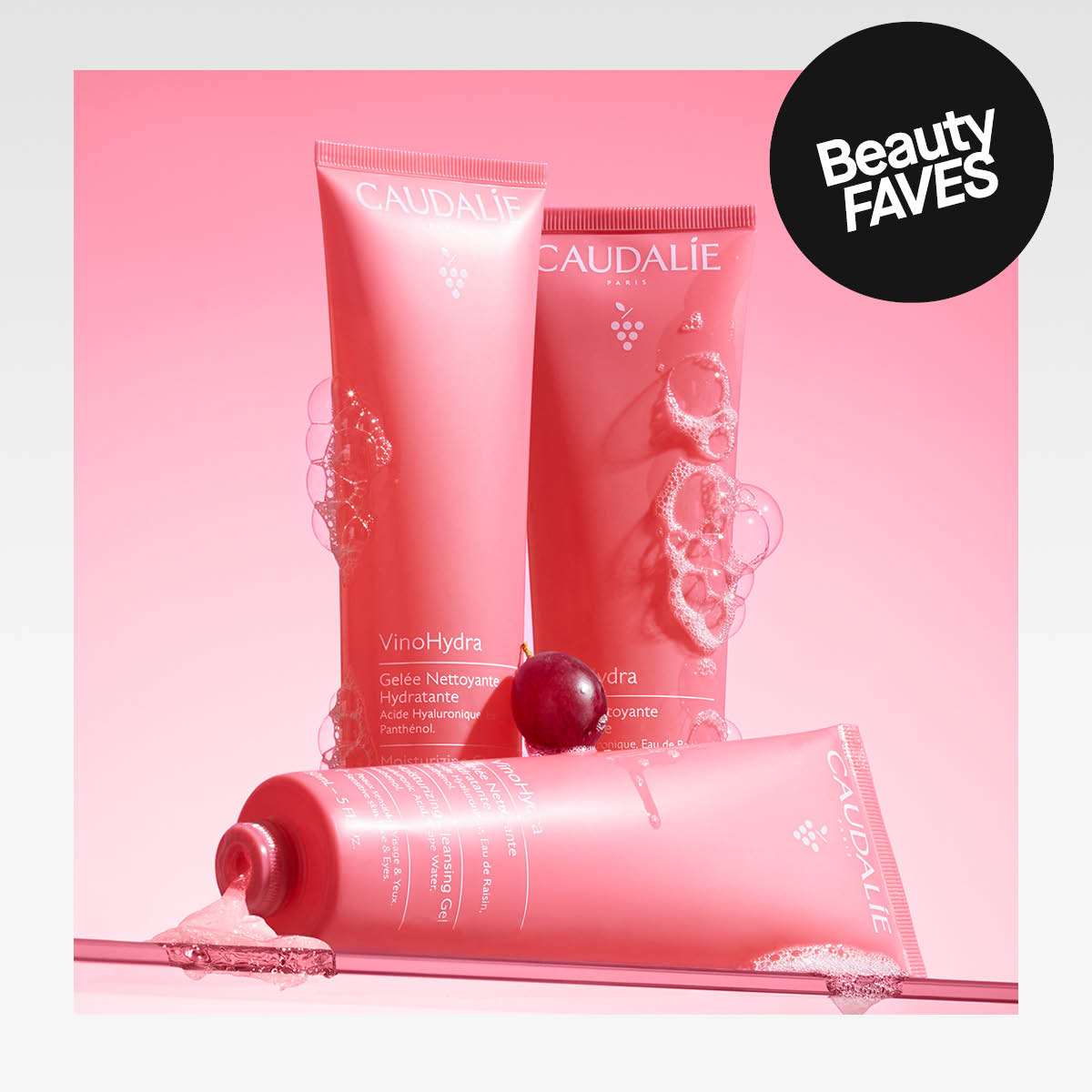Kolme vaaleanpunaista Caudalie-tuotetta, joiden reunoilla on vaahtoa, vaaleanpunaista taustaa vasten. Tarra, jossa lukee "Beauty Faves".