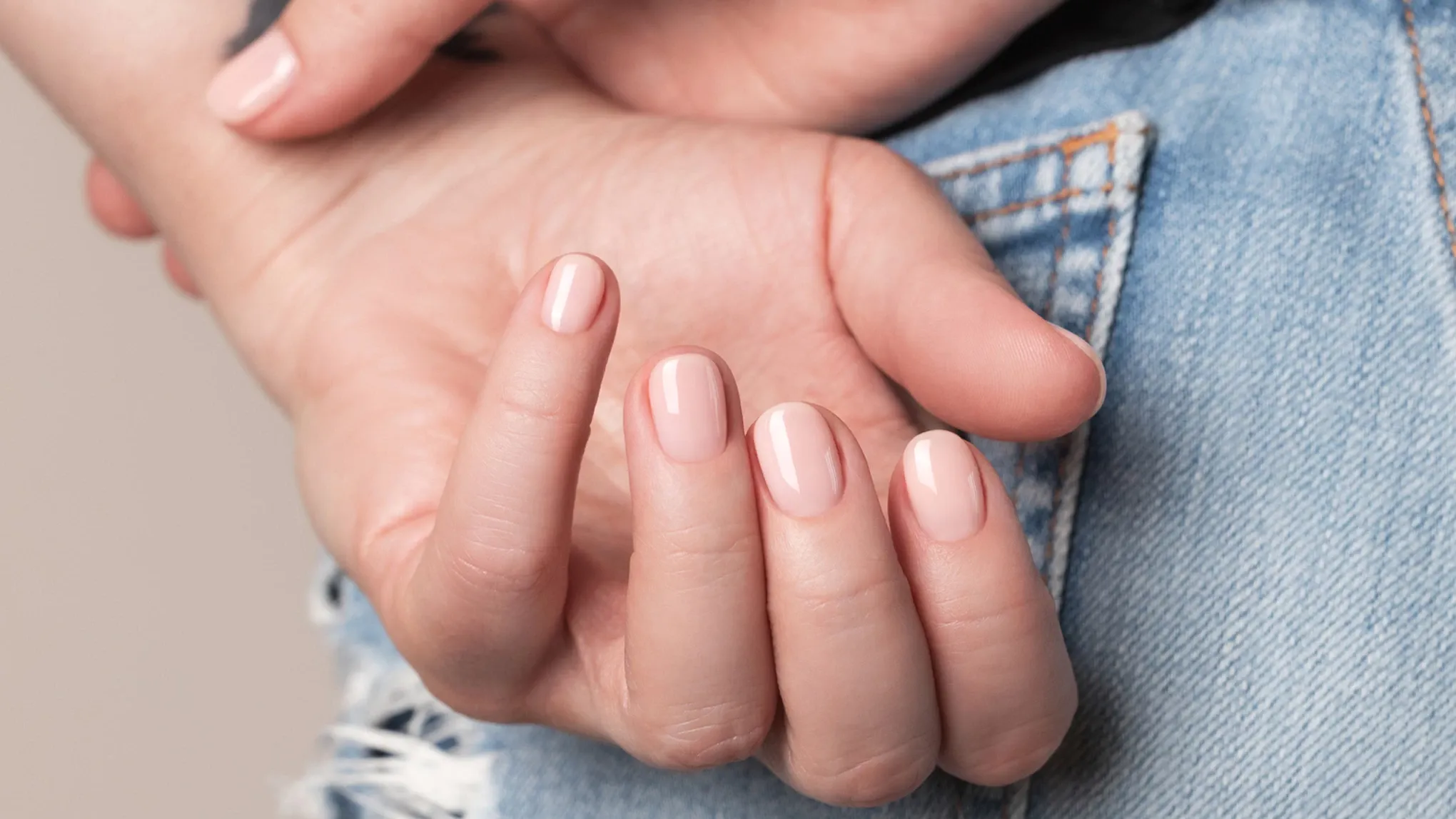 Närbild på en hand med ljusrosa nagellack.