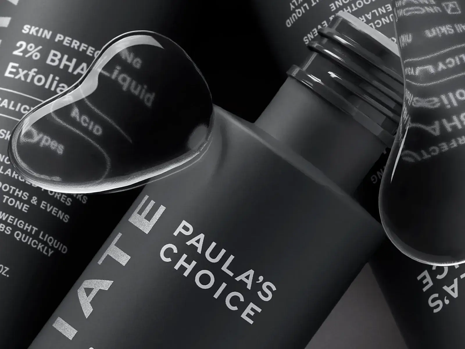 Kolme Paula's Choice -tuotetta lähikuvassa harmaalla taustalla ja vesipisaroita etualalla.