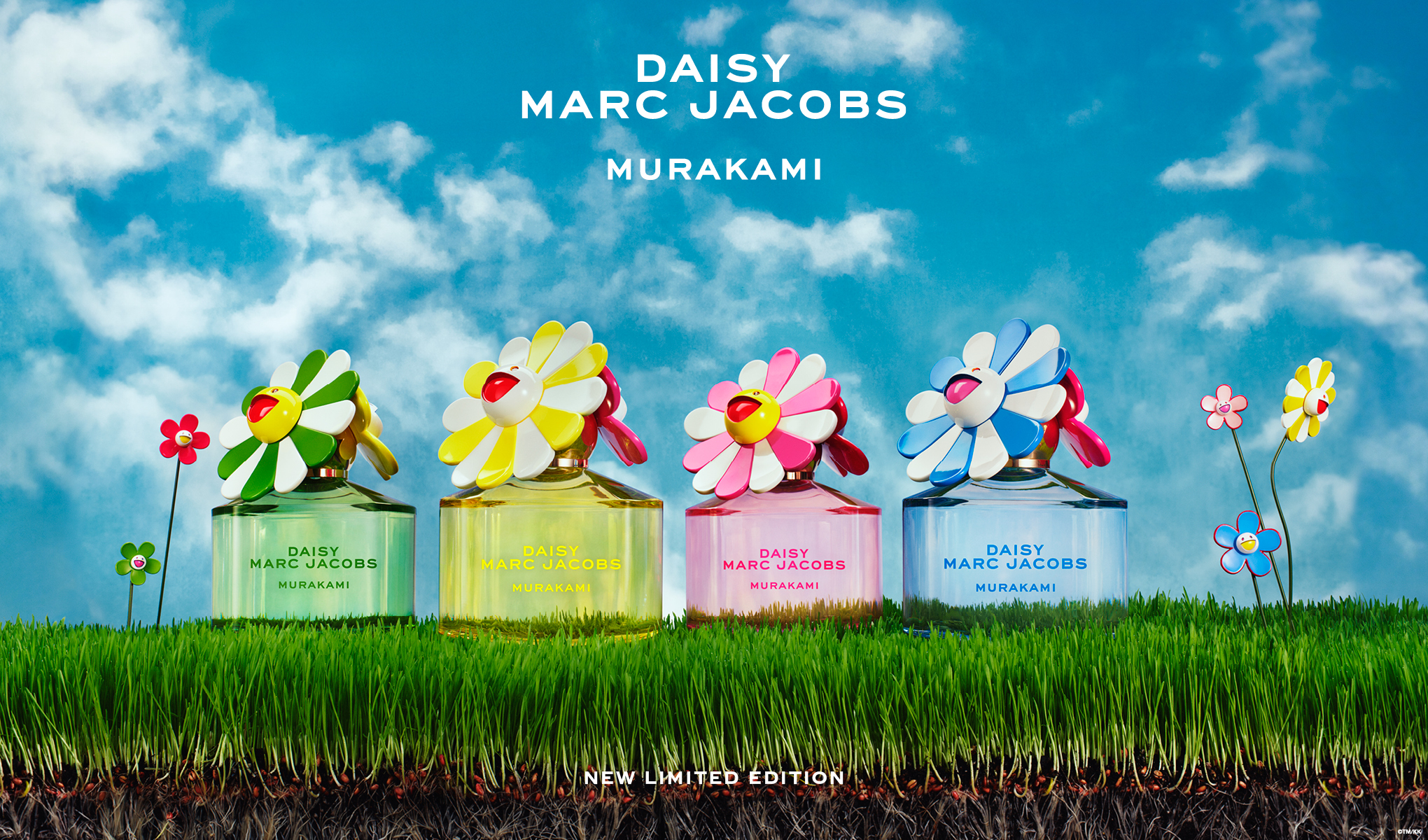 Fyra färgstarka Daisy Marc Jacobs Murakami-parfymer står på grönt gräs mot en blå himmel med moln. Flaskorna har lekfulla blomlock och är en limiterad utgåva.