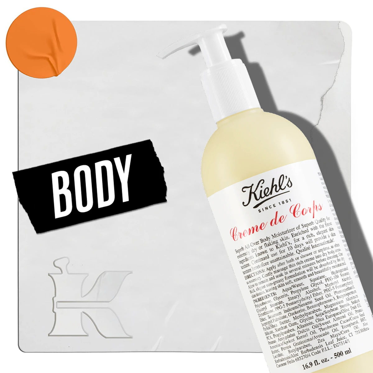 En flaske med Kiehl's Creme de Corps bodylotion med pumpe, plassert mot en lys bakgrunn. I nedre venstre hjørne står teksten «Body» og Kiehl's logo. En oransje sirkel er plassert i øvre venstre hjørne.