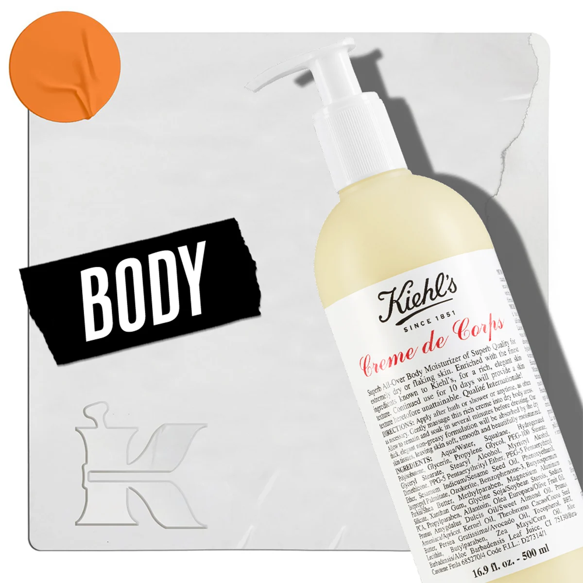 En flaska Kiehl's Creme de Corps kroppslotion med pump, placerad mot en ljus bakgrund. I nedre vänstra hörnet finns texten "Body" och Kiehl's logotyp. En orange cirkel är placerad i övre vänstra hörnet.